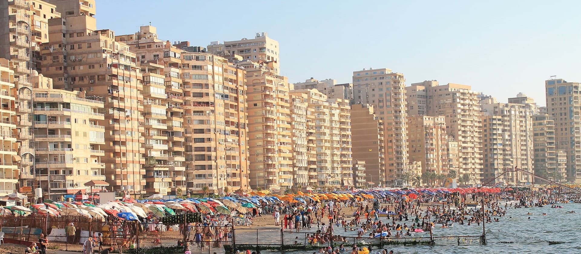 عمارات ميامي العالية على الكورنيش، وشماسي الشاطئ الملونة والمصطافون عند الماء في الصيف